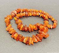 Photo of entire amber necklace arranged on dark background to show length and bead colors.