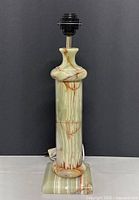 Lamp base made of polished onyx stone with natural color variations and veining, unlit state.