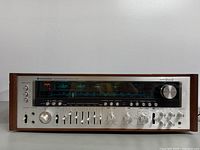 Straight-on front view of receiver showing tuning dial, controls and wood veneer sides.