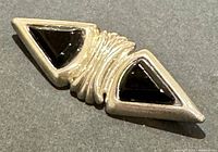 Close-up of the brooch showing the front design with two black triangular inlays set in silver.