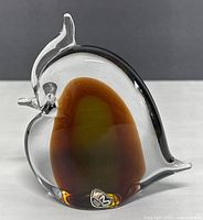 Front view of the art glass bird paperweight showing amber and green colored core