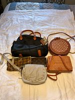 Overview of all 6 items including 4 purses and 2 wallets laid out on bedding showing mixed materials and colors.