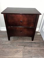 Front view of dark brown 2-drawer nightstand showing both drawers closed with round knobs and dark finish.