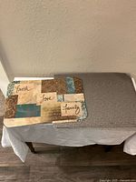 Single decorative placemat with Faith, Love, Family collage design in beige, brown, teal, and blue on a rectangular shape.