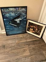 Two framed art prints leaning against wall on wooden floor, showing music and African American history themes.