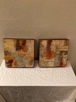 Two 12x12 inch prints on wood, titled Longevity and Prosperity, displayed side by side on a table with neutral background.