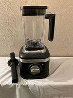 Full view of KitchenAid black and silver blender with container and tamper beside it.