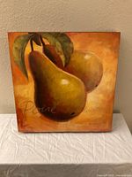 Front view of the art print depicting two pears with leaves, warm color palette in yellows, oranges, and browns.
