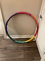 Photo of multicolor foam-covered weighted hula hoop standing against a wall showing full circular shape and colors