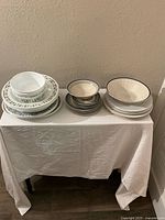 Photo showing a collection of various plates stacked in groups on a covered table.
