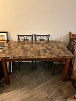 Rectangular dining table with faux marble-like tabletop and wooden legs, showing overall condition and material details