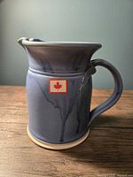 Blue ceramic pitcher with handle and spout, showing light to dark blue gradient glaze and artistic drips
