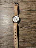 Full view of Fossil women's watch laid flat on wooden surface showing tan leather strap and watch face.