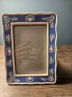 Front view of ceramic photo frame showing blue and white floral raised pattern
