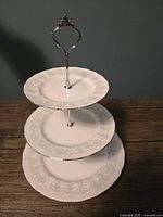 Full view of the 3-tier dessert stand with Silvertone metal handle and white bone china plates with floral design.