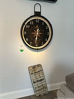 Black metal wall clock with compass star design and white numbers as a main feature on a white wall.