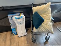 Commode chair with cream and blue pillows and white bath board in packaging next to it