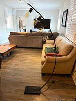 Full view of the black metal curved floor lamp with four clear bulbs and stone base in a living room setting.