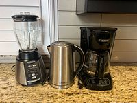Oster blender, Living Basics electric kettle, and Black & Decker coffee maker on kitchen counter.