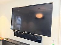 Front view of Sony flat screen TV mounted on wall with Sony soundbar attached beneath
