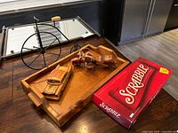Wooden tray with vehicle figurines alongside a boxed Scrabble game on a wooden surface