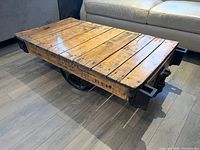 Three-quarter view of entire coffee table showing wooden top and cast iron wheels