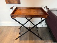 Side view of vintage folding side table with wooden tray and metal folding legs, showing tray handles and leg structure.