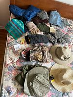 Photo of assorted adult hats and gloves/mittens on floral patterned bedding.