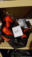 Orange and black cordless drill driver inside black bag with batteries and charger pack.