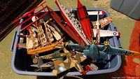 Wide view of model airplanes in plastic container including WWII fighter planes and model sailing ship