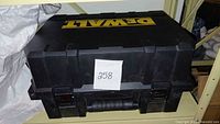 Black DEWALT branded hard carrying case closed with metal latches and black handle, labeled with lot number 258 on a white paper.