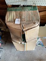Damaged cardboard packaging with printed label showing Home Gardener Multifunction Wheelbarrow and Hand Truck and capacity up to 300 lbs. Box is torn and taped, contents not visible.
