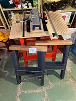 Full view of the IRON HORSE II sawhorses, worktable with wooden slat top, and miter saw box with handle and metal guides.