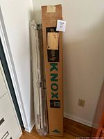 Knox Regent projection screen on tripod stand along with original box leaning against wall.