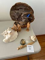 Seven decorative items on a table including wood, shells, and resin sphere.