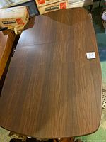Photo showing surface of rectangular dining table top with visible scratches, rounded edges, and straight grain finish.