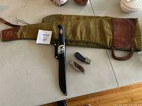 View of all items laid out including canvas carrying case, Rapala Marttiini fillet knife in sheath, folding knife with wooden handle, pocket knife with black handle