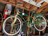 Side view of a Supercycle cruiser bicycle hanging in a garage. Bike is green and cream with various accessories.
