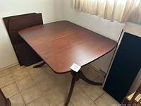 Full view of the wood dining table set up with extension leaves stored in the corner.