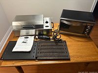 Kenyon City Grill with lid removed showing accessories and Oster toaster oven on table