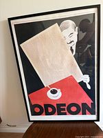 Full view of framed Odeon poster print leaning against wall