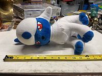 Side view of Pokémon Absol plush with measuring tape showing approx. 11 inches length.