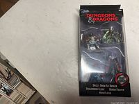Front view of the unopened box containing three die cast Dungeons & Dragons figurines: Dreezle Drow Elf Ranger, Dragonborn Cleric, and Human Fighter Mind Flayer.