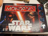 Star Wars Monopoly game box cover showing the Star Wars logo and characters Kylo Ren and Rey with lightsabers.