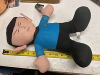 Full horizontal view of Mr Spock plush doll laying down next to measuring tape showing approximately 12 inches length.