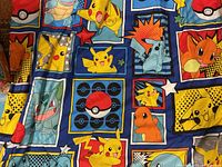 Close-up photo showing colorful squares with Pokemon characters Pikachu, Charmander, Squirtle, Bulbasaur, and other iconic designs including Pokéballs and stars.