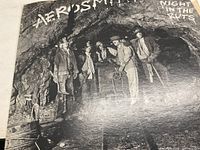 Front cover of Aerosmith 'Night In The Ruts' album showing band members in a cave setting.