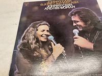 Front cover of the vinyl record album showing Johnny Cash and June Carter Cash singing.