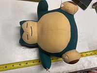 Top view of Snorlax plush showing body, face and limbs, measuring about 15 inches in length.