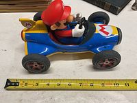 Side view of Super Mario toy car with Mario figure inside, showing length approximately 10 inches.
